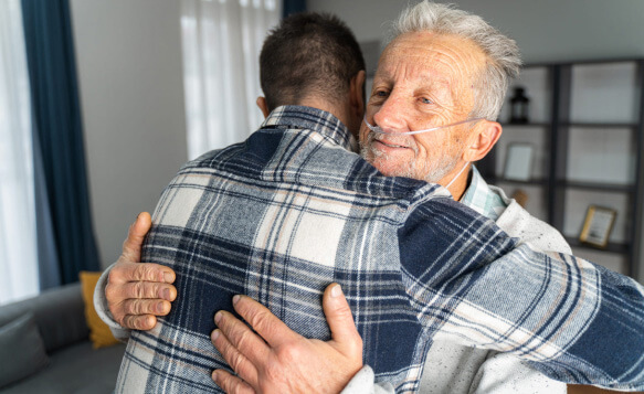 caregiver hugging resident who is wearing a nasal canula